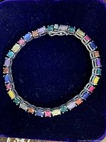 Top view of bracelet on blue velvet background showing full circle of multicolored stones and silver settings