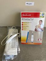 Both heating pads: boxed Sunbeam unit beside sealed-bag Kaz pad