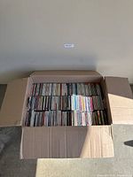 Open cardboard box showing first layer of CDs aligned in rows