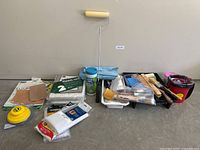 Full lot overview on floor showing roller, pail, brushes, sanding supplies, drop cloths