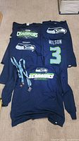 Overview of four navy Seahawks shirts and two lanyards