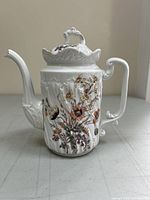Front and side view of Haviland antique porcelain coffee pot showing floral decoration and embossed patterns