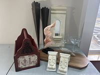 Overview of all items in the lot showing wall hanging, stone sculpture, white corbels, glassware, bird figurine, and candle holders