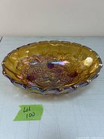 Top and angled view of large carnival glass bowl showing grapes motif and scalloped edges with iridescent amber finish