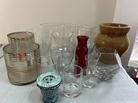 Photo showing 13 decorative vases with varied shapes and materials on a table