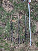 Metal vine panel with leaf decorations and curved frame lying on grass with measurement tape