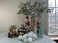 Wide view showing all Christmas decor items including snow globe, nutcracker, Santa figurines, berry branches in vase, candlesticks, ceramic trees, and ornaments.