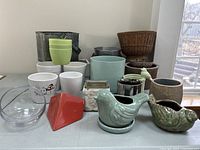 Photo showing various assorted planters including ceramic bird-shaped planters, small glass bowl, plastic pots, metal pots, and rattan basket planter.
