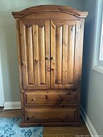Front view of the pine wood wardrobe with closed double doors and two drawers at the bottom.
