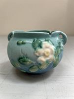 Side view of small round ceramic jaedinière with soft blue-green glaze and white rose floral relief.