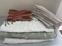 Stack of folded table linens including napkins and tablecloths in various colors and patterns, arranged on top of each other.