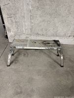 Front and side view of used aluminum work platform bench on concrete floor