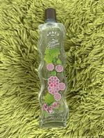 Wavy-shaped glass bottle with pink flowers and black screw cap