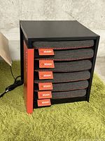 Front view of black metal heating station with five grey Stoov cushions installed