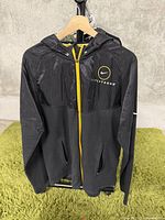 Front view of black Nike Livestrong jacket with yellow zipper and pockets showing the emblem on chest.