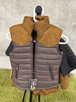 Front view of kids puffer vest showing brown suede-like shoulder area and collar, gray quilted padded body with zippered pockets.