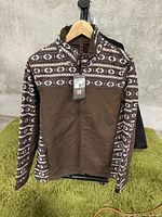 Front view of men's jacket showing brown color with patterned upper chest and sleeves, full zipper, and standing collar.