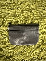 Front view of the small black leather money pouch showing the Michael Kors embossed logo.