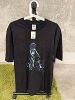 Full front view of the black T-shirt showing the astronaut riding a bicycle graphic on front.