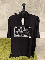 Front view of new black XL T-shirt with white bicycle/cassette tape graphic design