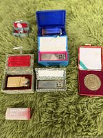 Four vintage seal stamps inside their original decorative boxes on a green textured surface, showcasing varied materials and intricate designs.