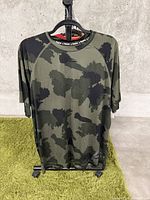 Front view of green and black camouflage short sleeve T-shirt on hanger