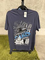 Front view of navy blue large t-shirt with Paris themed graphic print showing landmarks and text.