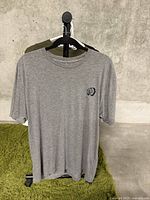 Front view of gray XL T-shirt showing small black logo on front left chest.