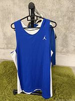 Front view of blue Jordan basketball tank top with white Jumpman logo on left chest area