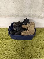 Bin with piled women's boots, black and tan colors visible, with varied materials including leather and fur lining.