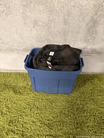 Blue bin containing folded brown plaid shirt or jacket