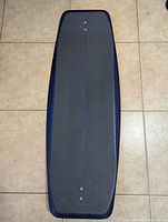 Top side of the BoardRoom wakeskate board showing the grey textured grip area and dark blue border on a tiled floor.