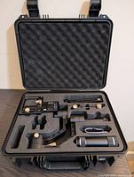 Open hard case with foam insert holding gimbal body, handle, mounting plate, USB cable and tripod base
