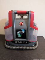 Front view of Hoover Spotless cleaner showing logo, self cleaning label, and hose wrapped at base
