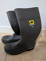 Side profile photo showing both black rubber Dakota Work Pro Series boots with yellow and white logo on the shaft.