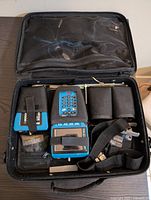 Top-down view of the carrying case opened showing the tester units, cables, and accessories organized inside.