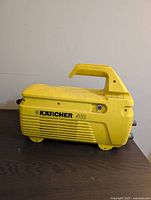 Side view of yellow Karcher 410 pressure washer with visible handle, ventilation slots, and model label.