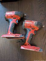 Two Hilti SID 4-A22 impact drivers placed side by side on a wooden surface, showing front-side and grip area.