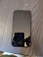 Front view of black iPhone XR with screen off showing light fingerprints and reflections on screen.