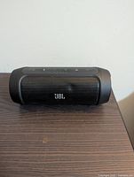 Front view of the JBL Charge 2 speaker showing the JBL logo and control buttons on top.