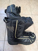 Photo showing side profile of black K2 Brigade snowboarding boots with gold accents and laces on tiled floor.