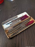 Miniature metal files stored in a metal tin showing varying blade shapes and number of files