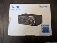 Box of the mini projector featuring product image and specifications like HDMI support, easy setup, remote control, stereo speakers.