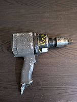 Top view of Ingersoll Rand pneumatic impact wrench on dark surface, showing worn grey finish and yellow paint markings.