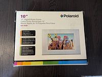 Box for Polaroid 10 inch digital photo frame showing model XSA-101695 and specifications, 10 inch color screen, 512 MB internal storage, reads nearly all digital memory cards.