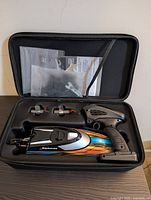 Open carrying case showing Alpharev branded remote control boat, two controllers, and instruction manuals in mesh pocket