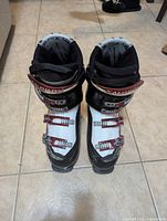 Top-down view of pair of white Salomon Mission X5 ski boots with black and red buckles and straps, size 27.