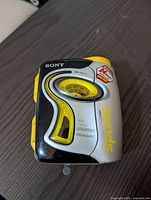 Front view of the Sony WM-FS111 cassette Walkman showing analog AM/FM radio dial, Sony logos, and sport branding with a black, yellow, and silver color scheme.