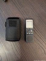 Black Sony ICD-PX820 digital voice recorder and black protective carrying case placed side by side on a wooden surface.