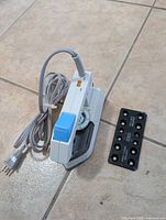 Photo of white and blue ski waxing iron with attached power cord and separate black plastic scraper.